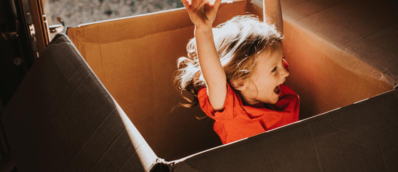 Kid jumps in a cartboard box